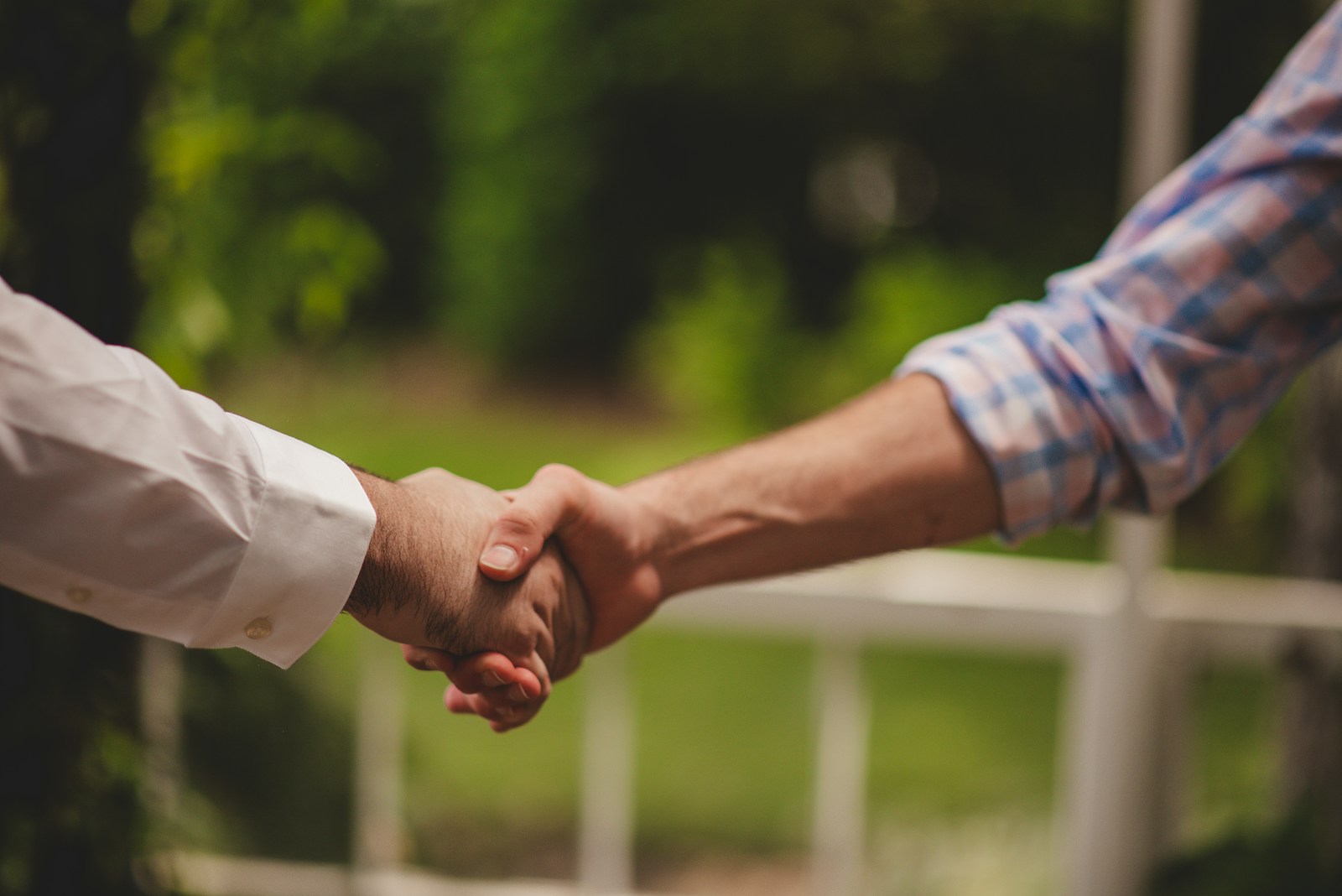 Zwei Menschen geben sich im Garten die Hand