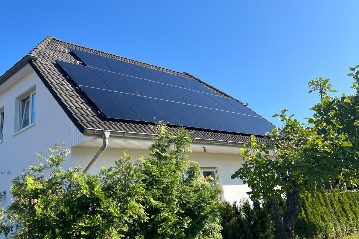 Wohnhaus mit Photovoltaikanlage, im Vordergrund ein bewachsener Garten